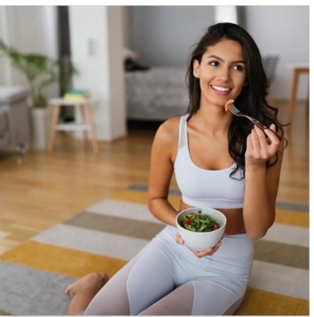 Frau isst einen Salat auf einer Yogamatte