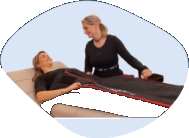 Therapeutin führt eine Lymphdrainage an einer liegenden Patientin durch